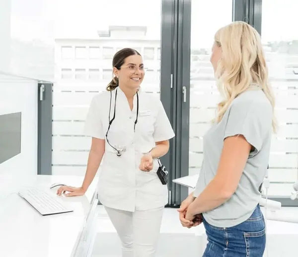 Zahn&auml;rztin und Patientin stehen im Behandlungszimmer und sprechen &uuml;ber den Behandlungsplan